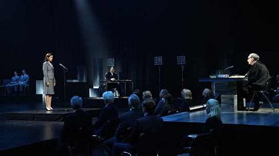 Dorka Gryllus (stehend), Clemens Schick (am Tisch hinten), Rainer Bock (rechts) in "Die Ermittlung" (2024)